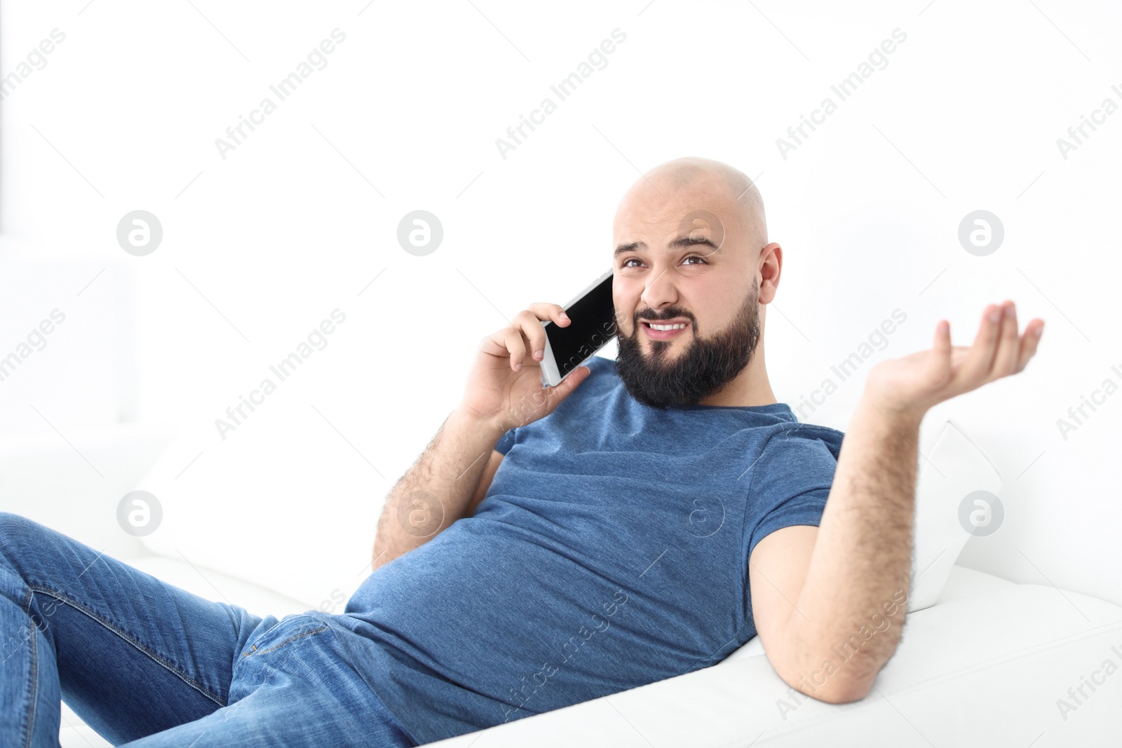 Photo of Portrait of young man talking on mobile phone on sofa
