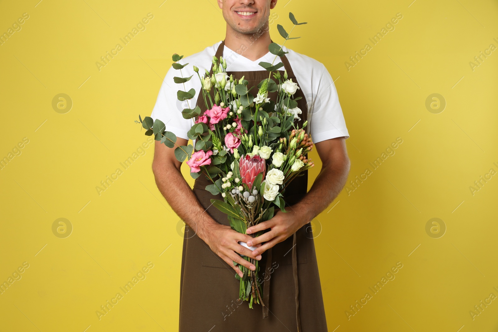 Photo of Florist with beautiful bouquet on yellow background, closeup