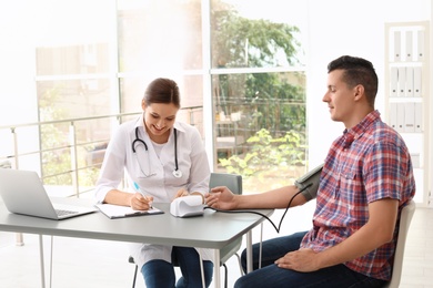 Doctor checking patient's blood pressure in hospital