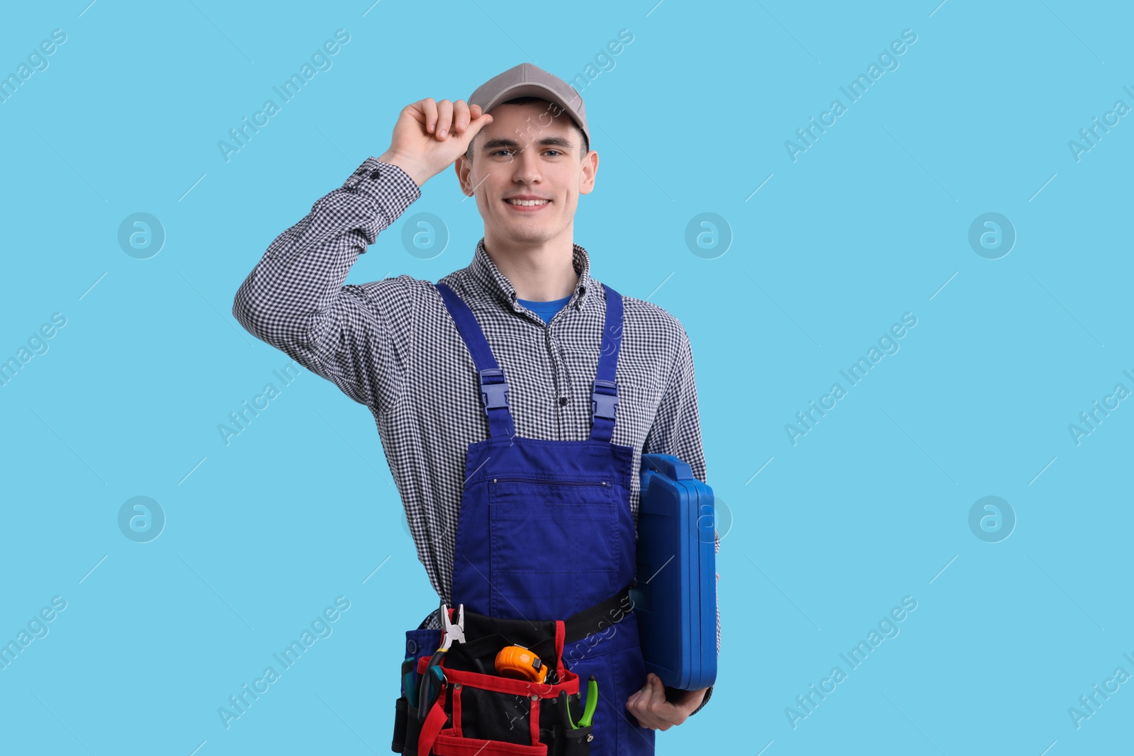 Photo of Professional repairman with tool box on light blue background