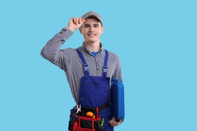 Professional repairman with tool box on light blue background