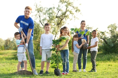 Kids planting trees with volunteers in park