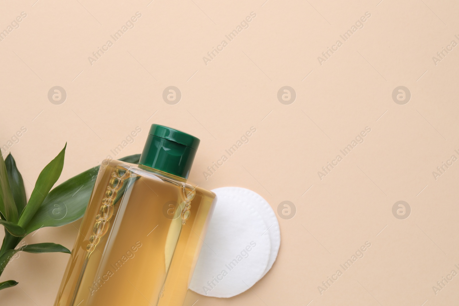 Photo of Micellar water and cotton pads on beige background, flat lay. Space for text