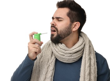 Photo of Young man with scarf using throat spray on white background