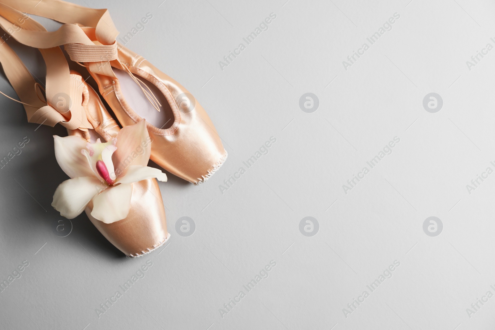 Photo of Ballet shoes. Elegant pointes and orchid flower on grey background, flat lay. Space for text