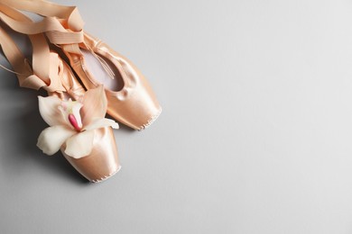 Photo of Ballet shoes. Elegant pointes and orchid flower on grey background, flat lay. Space for text