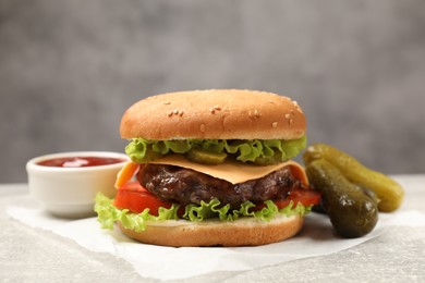 Photo of Tasty hamburger with patty, sauce and pickles on light grey table, closeup