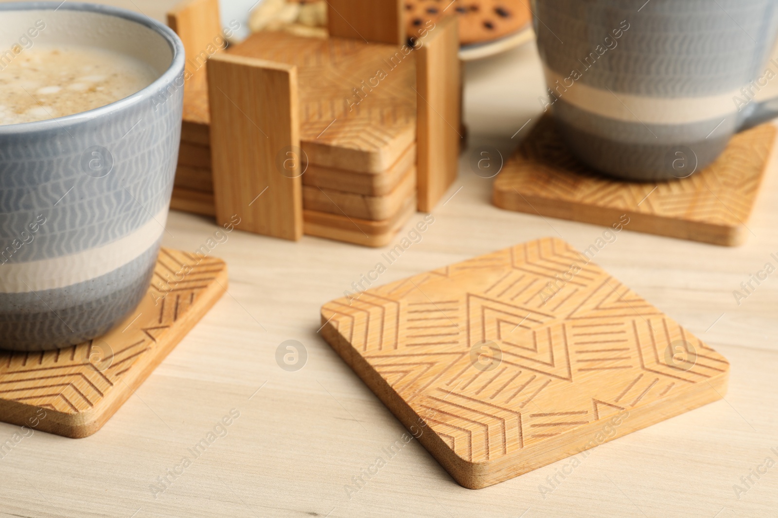 Photo of Stylish wooden cup coasters and mugs on table