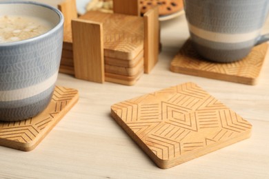 Photo of Stylish wooden cup coasters and mugs on table