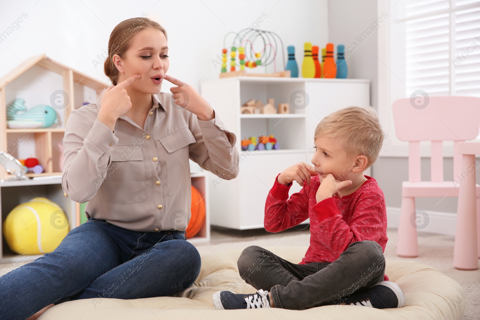 Photo of Speech therapist working with little boy in office