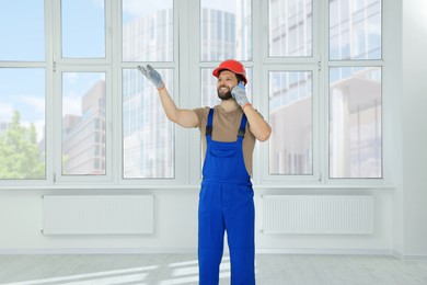 Photo of Professional repairman in uniform talking on phone indoors