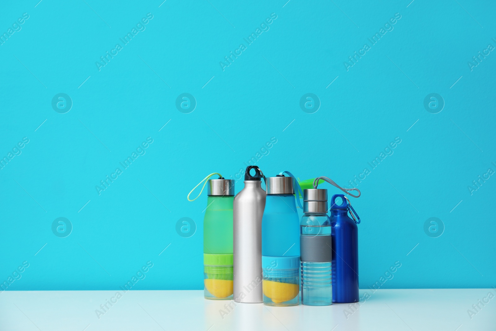 Photo of Different water bottles for sports on color background. Space for text