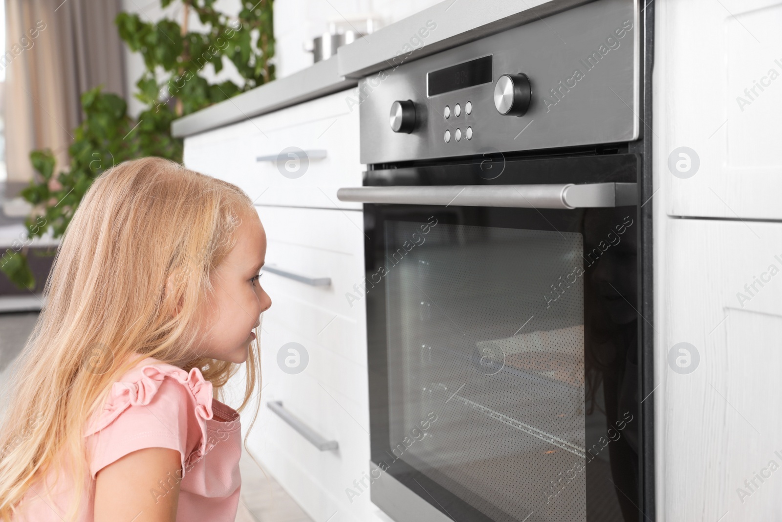 Photo of Little girl baking something in oven at home