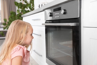 Little girl baking something in oven at home