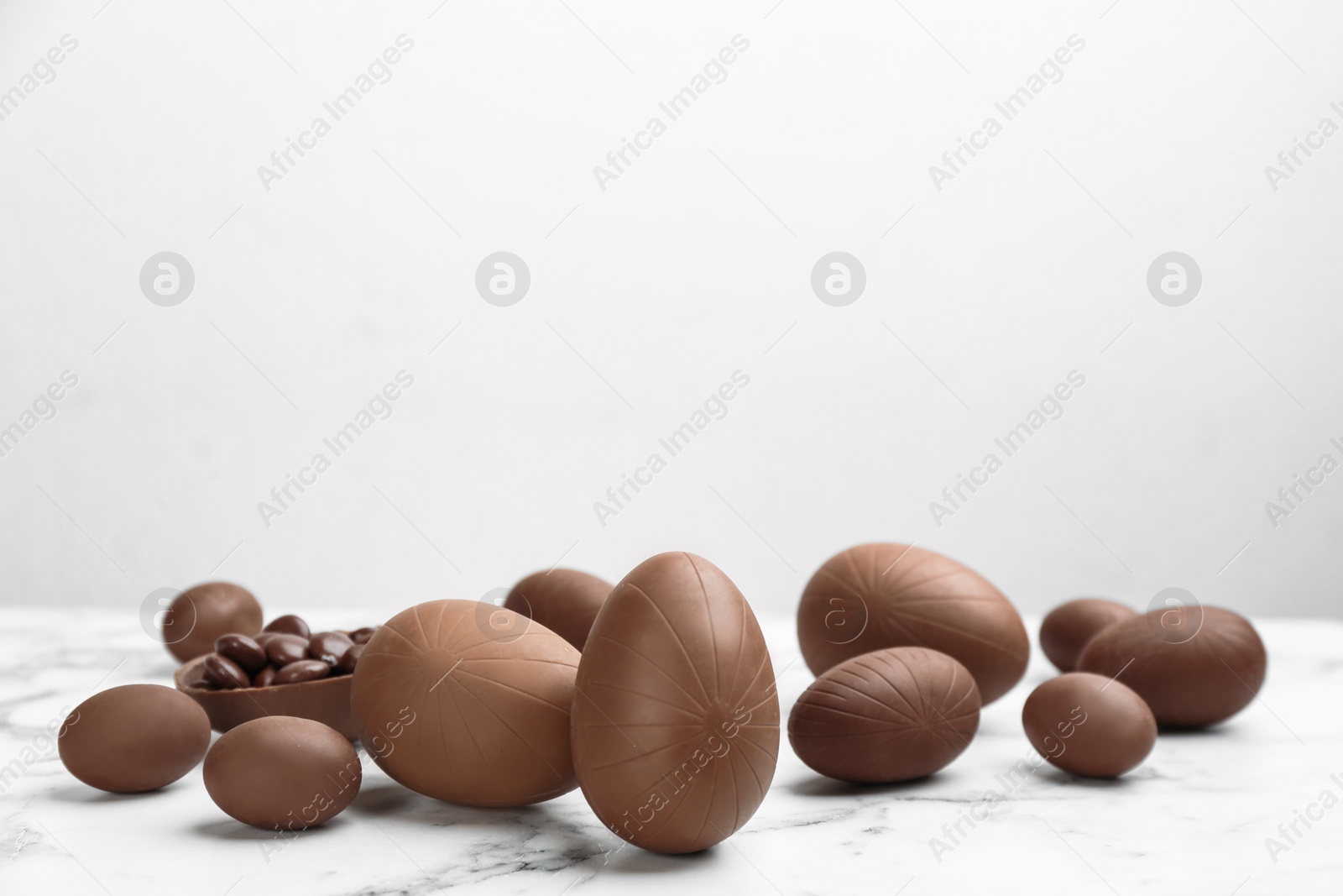 Photo of Sweet chocolate eggs on white marble table. Space for text