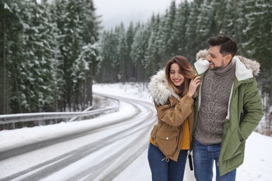 Photo of Couple walking near snowy forest, space for text. Winter vacation