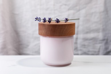 Photo of Jar of hand cream and lavender on white table