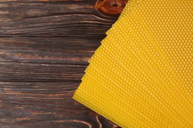 Natural beeswax sheets on wooden table, flat lay. Space for text