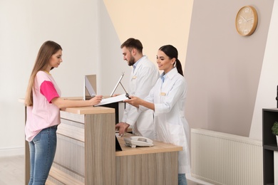 Photo of Professional receptionists working with patient at desk in modern clinic