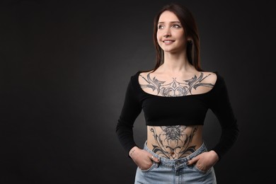 Photo of Portrait of smiling tattooed woman on black background. Space for text