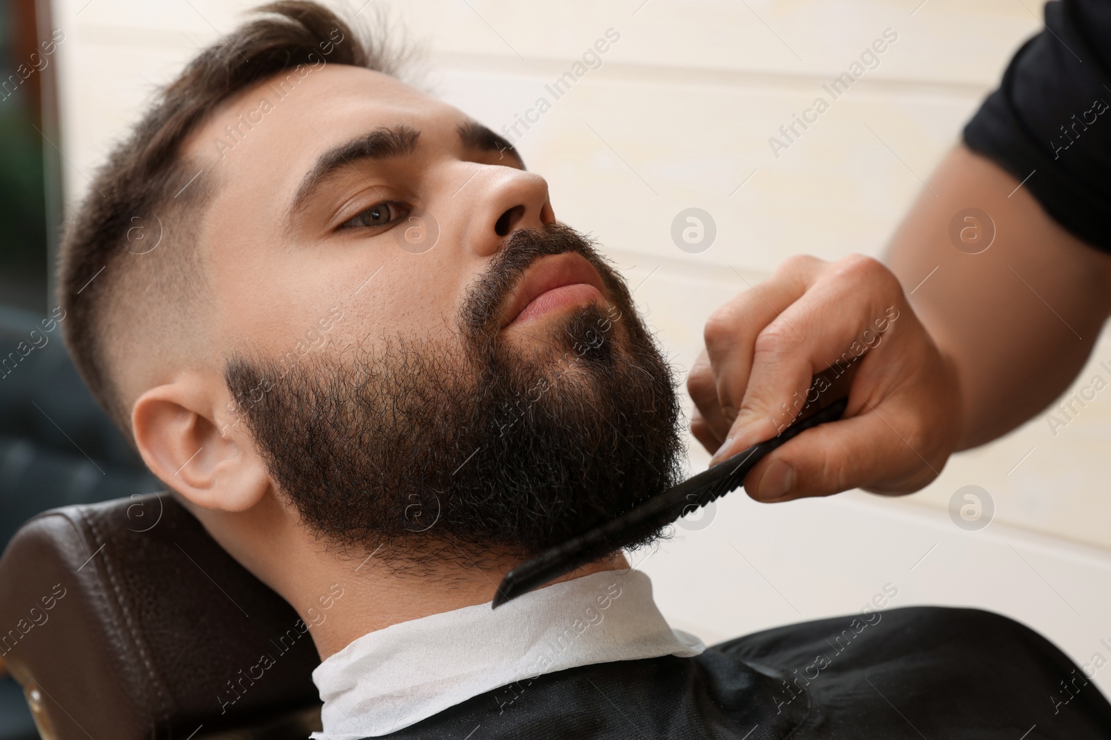 Photo of Professional hairdresser working with client in barbershop, closeup