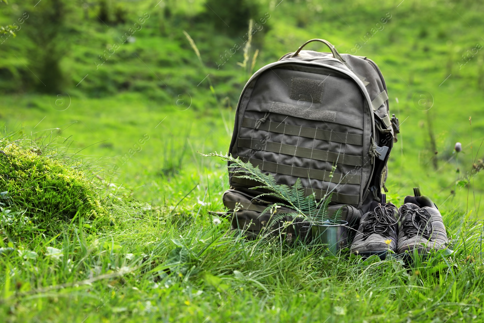 Photo of Backpack and hiking boots in green mountain valley. Summer camping