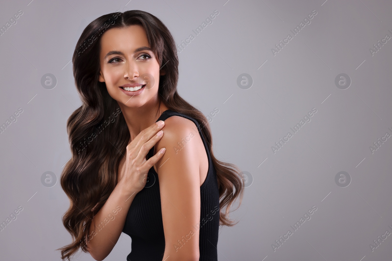 Image of Gorgeous woman with shiny wavy hair on grey background, space for text. Professional hairstyling