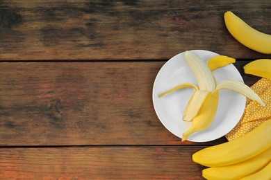 Many delicious ripe bananas on wooden table, flat lay. Space for text