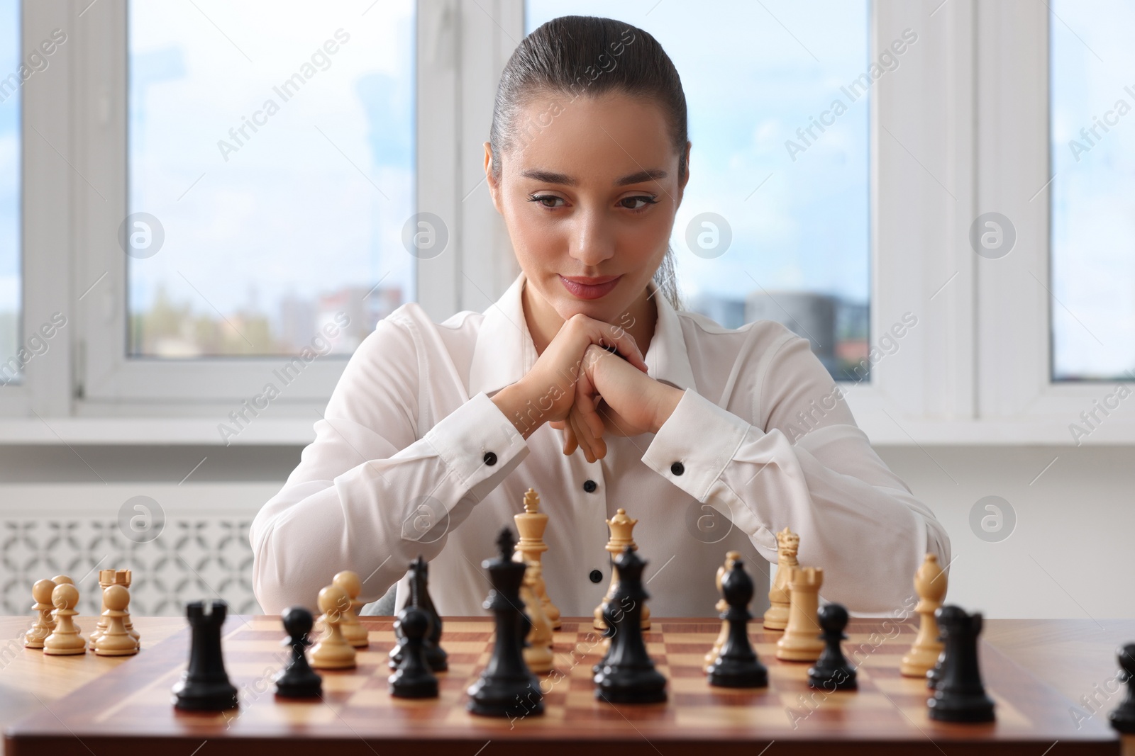 Photo of Woman playing chess during tournament at table indoors