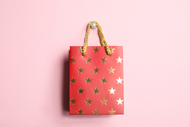 Photo of Red shopping paper bag with star pattern on pink background