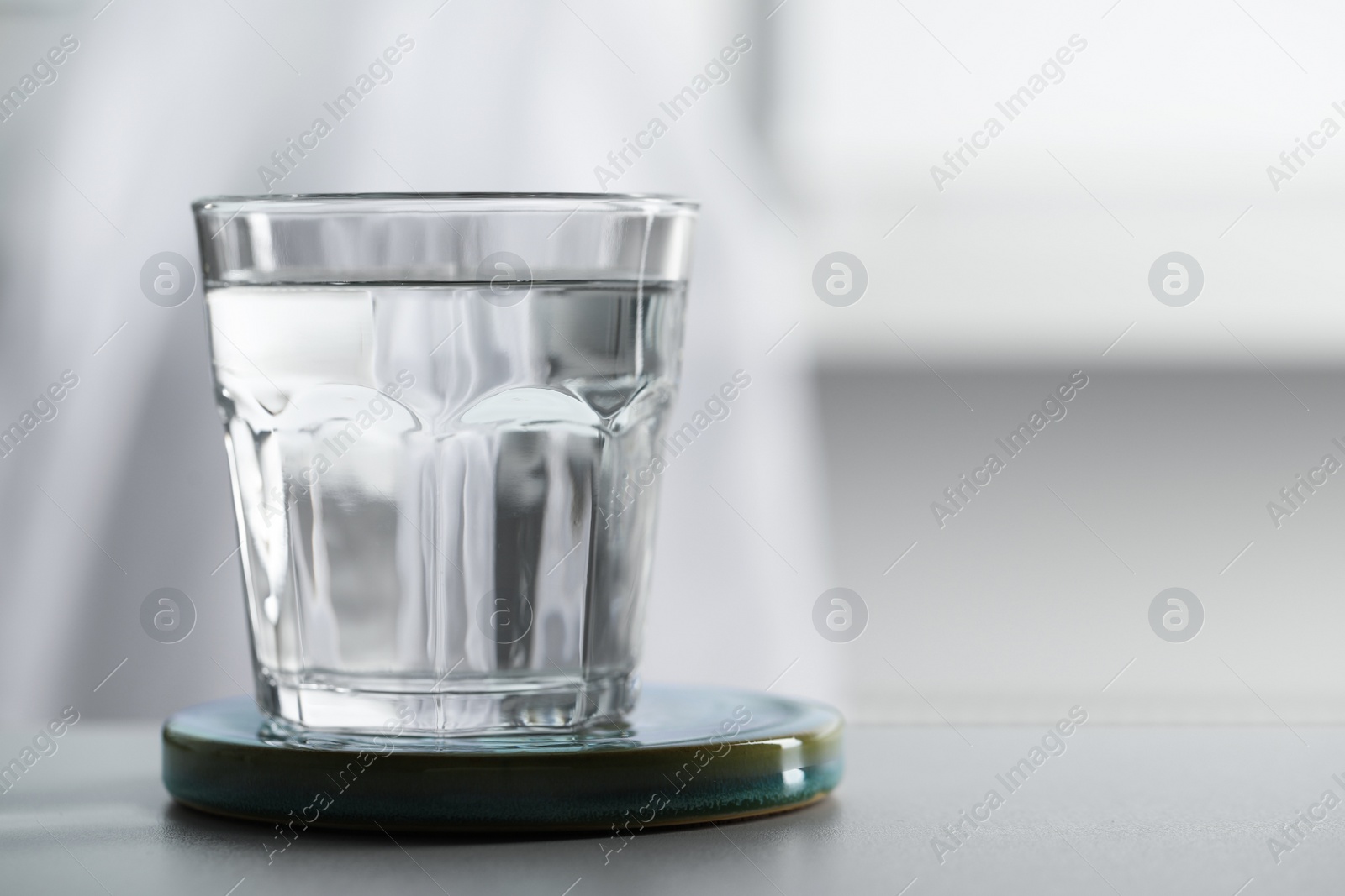 Photo of Glass of pure water on light table against blurred background, space for text