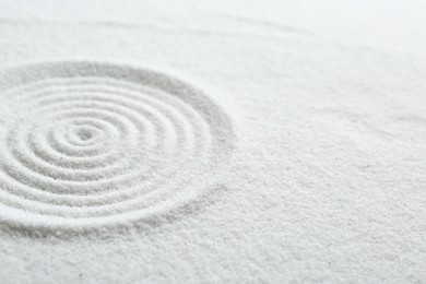 Photo of Zen rock garden. Circle pattern on white sand, closeup. Space for text