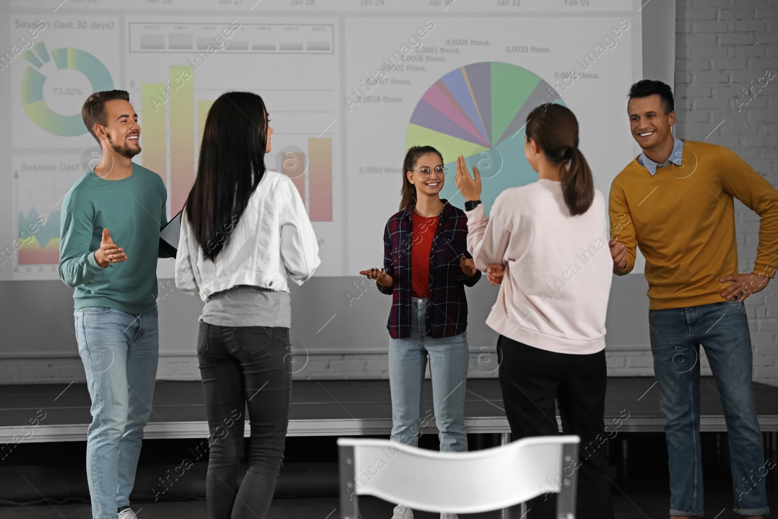 Photo of Young people having business training in conference room with projection screen