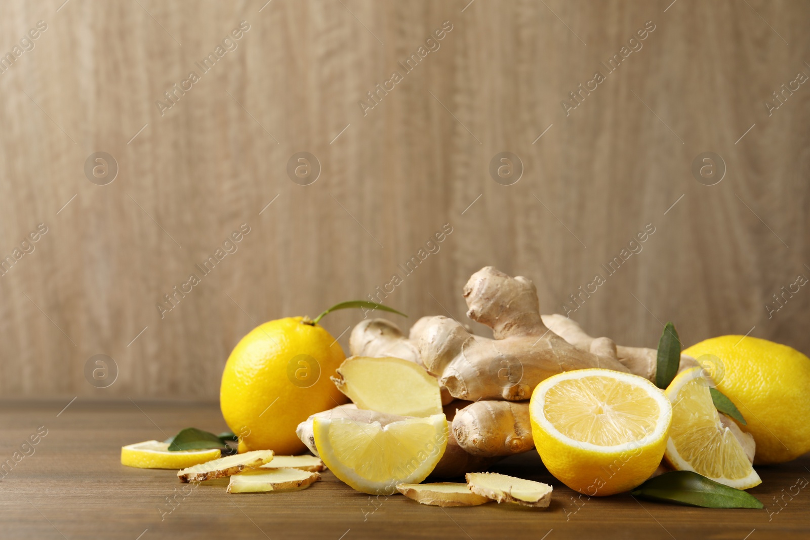 Photo of Fresh lemons and ginger on wooden table. Space for text