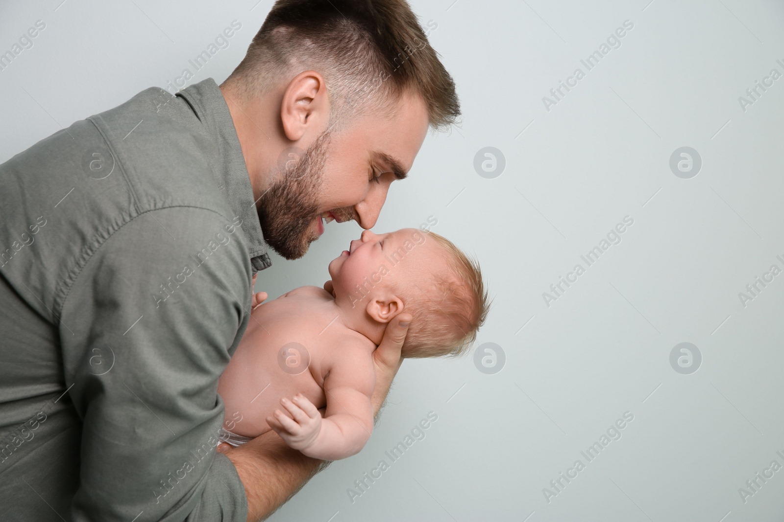 Photo of Father with his newborn son on light grey background