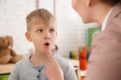 Speech therapist working with little boy in office