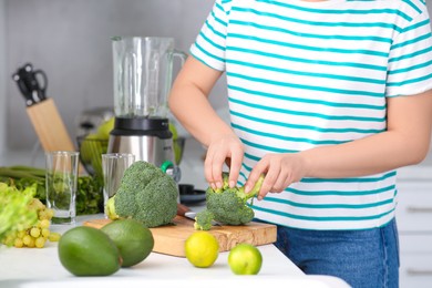 Woman cutting broccoli for smoothie in kitchen, closeup