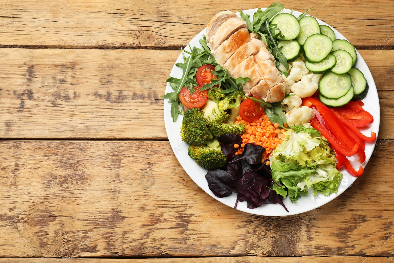 Photo of Balanced diet and healthy foods. Plate with different delicious products on wooden table, top view. Space for text