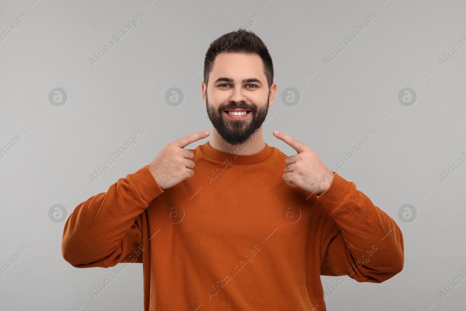 Photo of Man showing his clean teeth and smiling on gray background