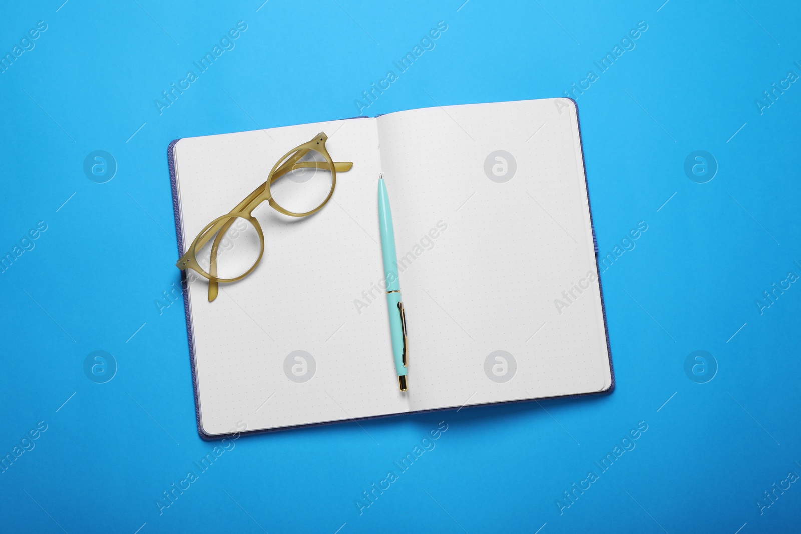 Photo of Open notebook, pen and glasses on light blue background, top view