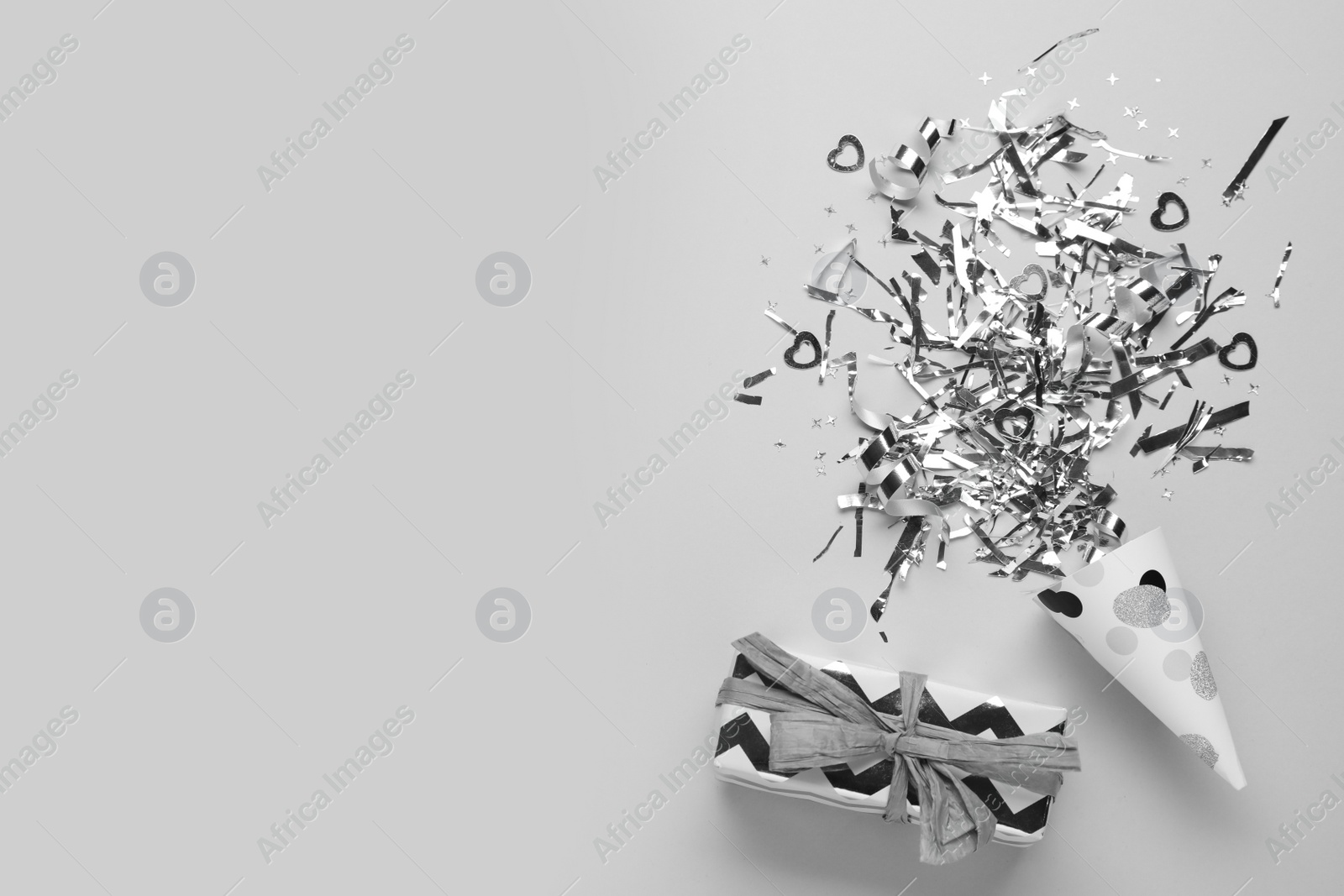 Photo of Flat lay composition with shiny silver confetti and box on light grey background. Space for text