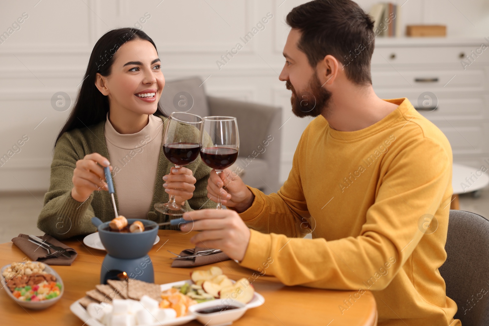 Photo of Affectionate couple enjoying chocolate fondue during romantic date at home