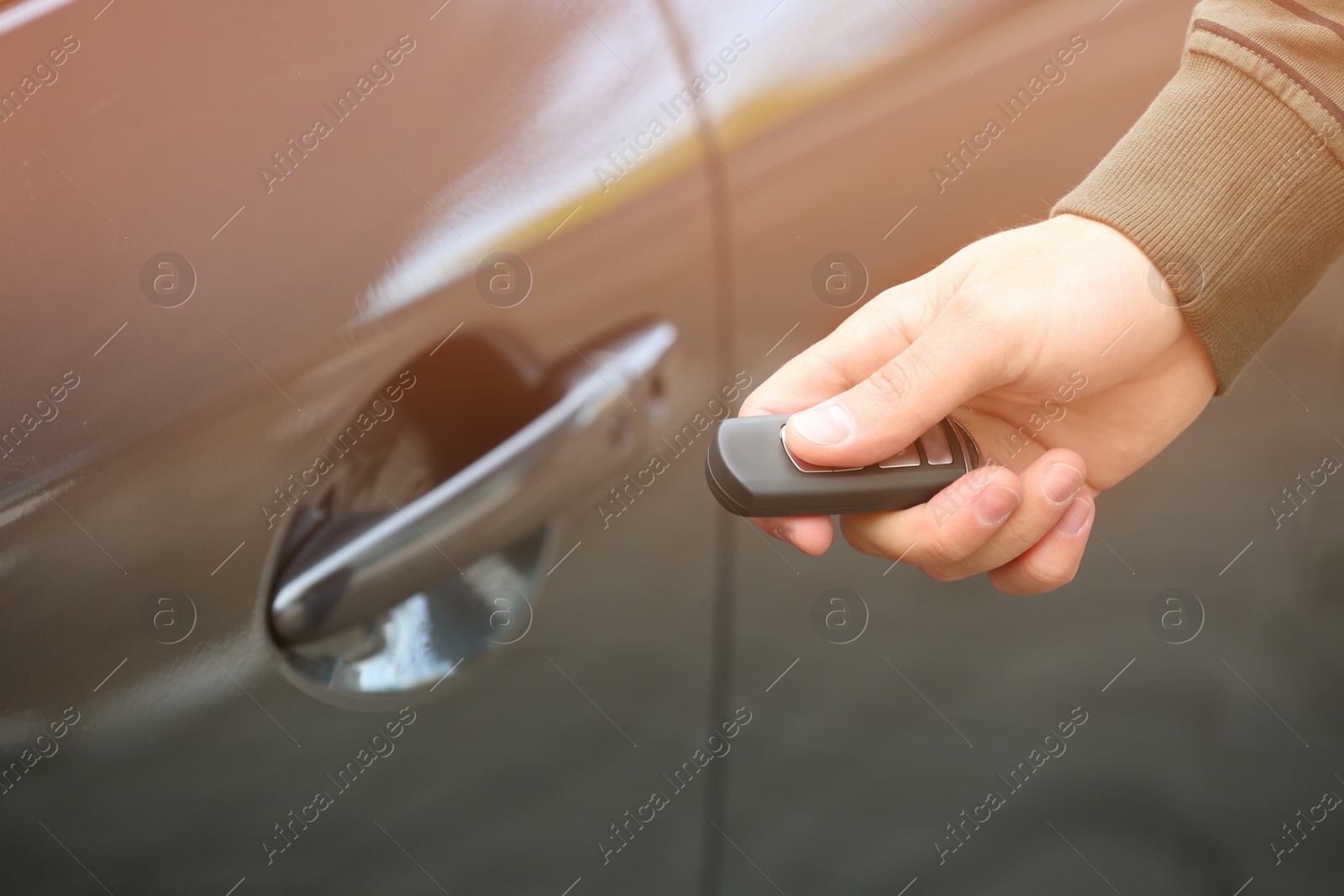 Photo of Closeup view of man opening car door with remote key