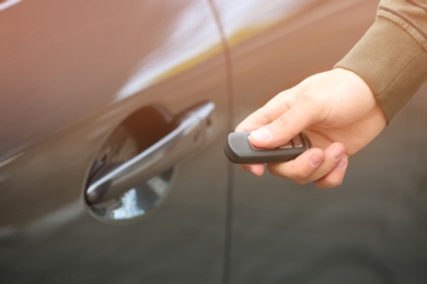 Photo of Closeup view of man opening car door with remote key