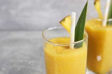 Photo of Tasty pineapple smoothie on light gray table, closeup. Space for text