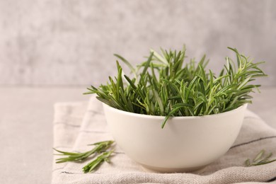 Bowl with fresh green rosemary on light grey table, closeup. Space for text