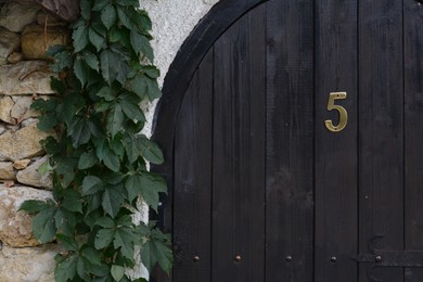 Photo of House number five on wooden door outdoors