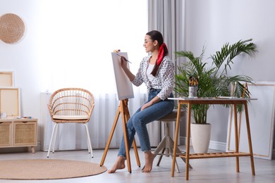 Photo of Happy woman artist drawing picture on canvas in studio