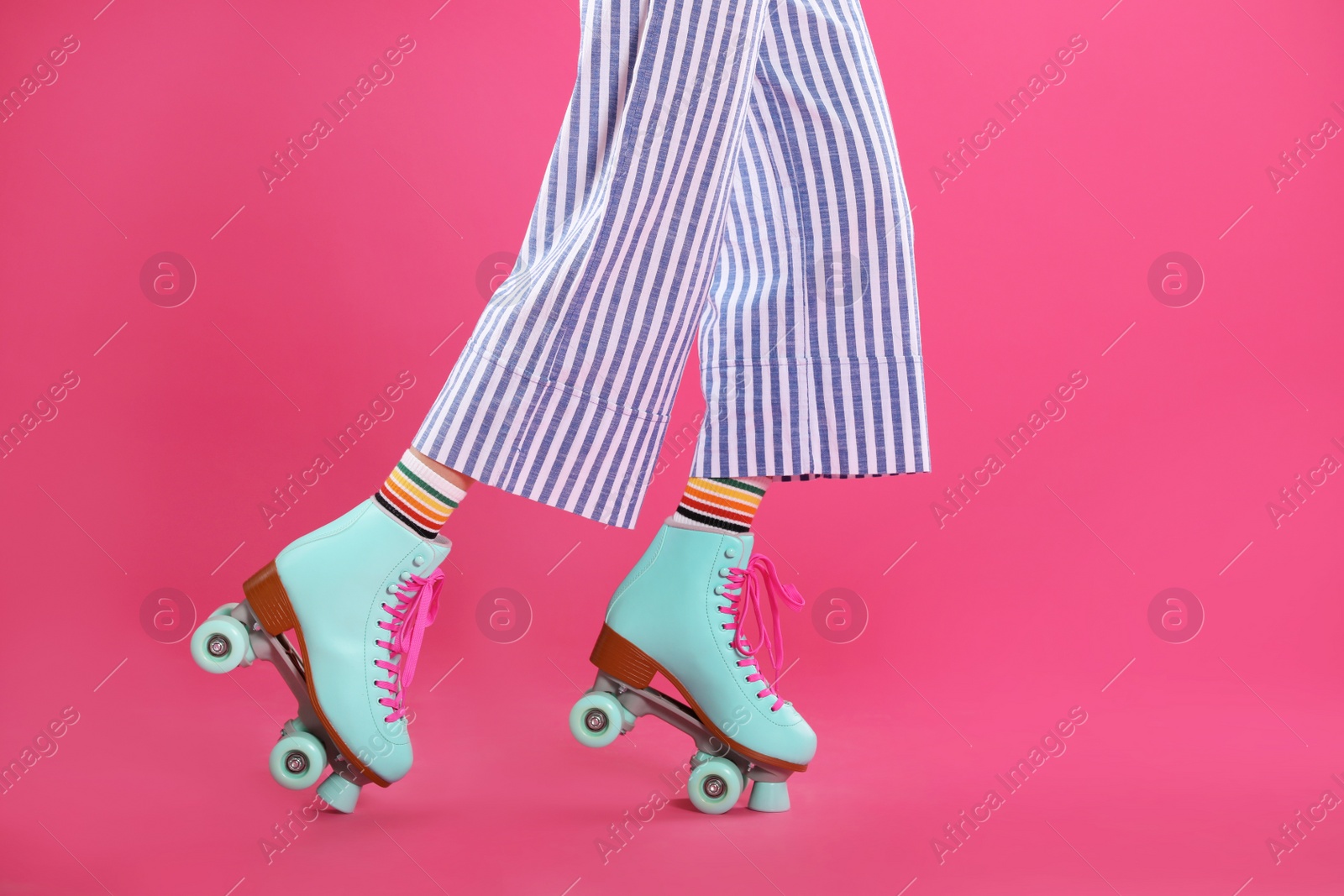 Photo of Young woman with retro roller skates on color background, closeup