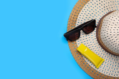Photo of Straw hat, sunscreen and sunglasses on light blue background, flat lay and space for text. Beach accessories